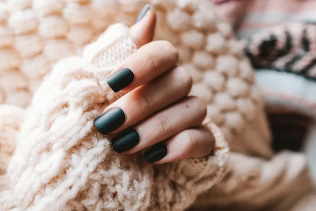 Mains aux ongles soignés enveloppées dans un pull en laine, ambiance douce et apaisante
