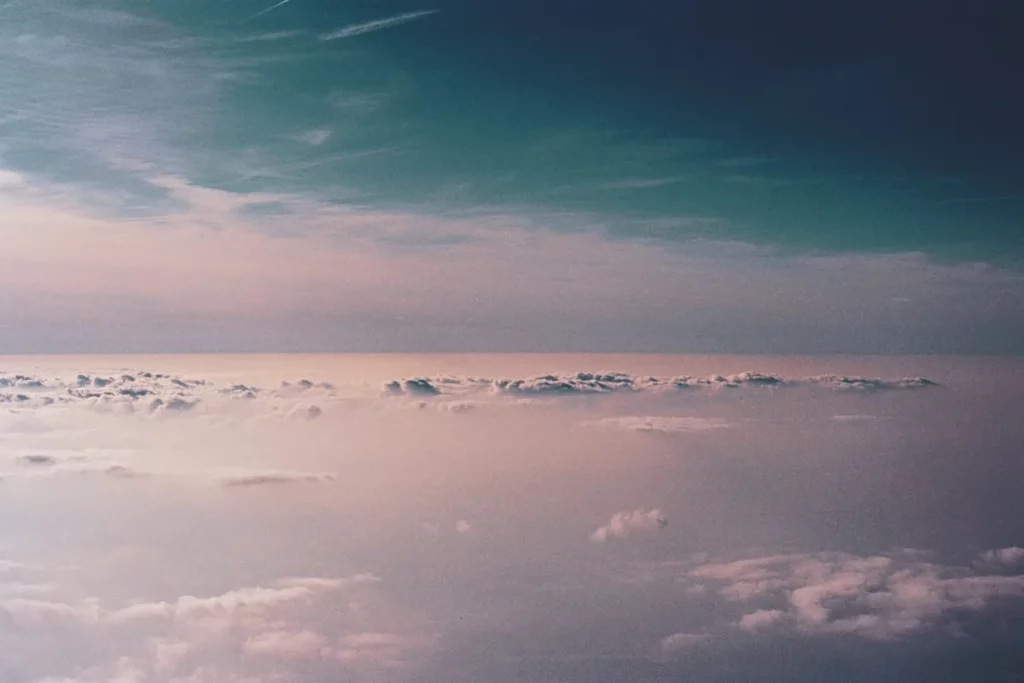Mer de nuages aux teintes rosées au coucher du soleil, vue du ciel, évoquant le calme et l'apaisement