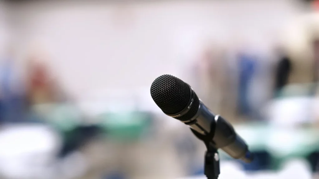 Micro sur pied devant une salle floue — hypnose et peur de parler en public à Lausanne